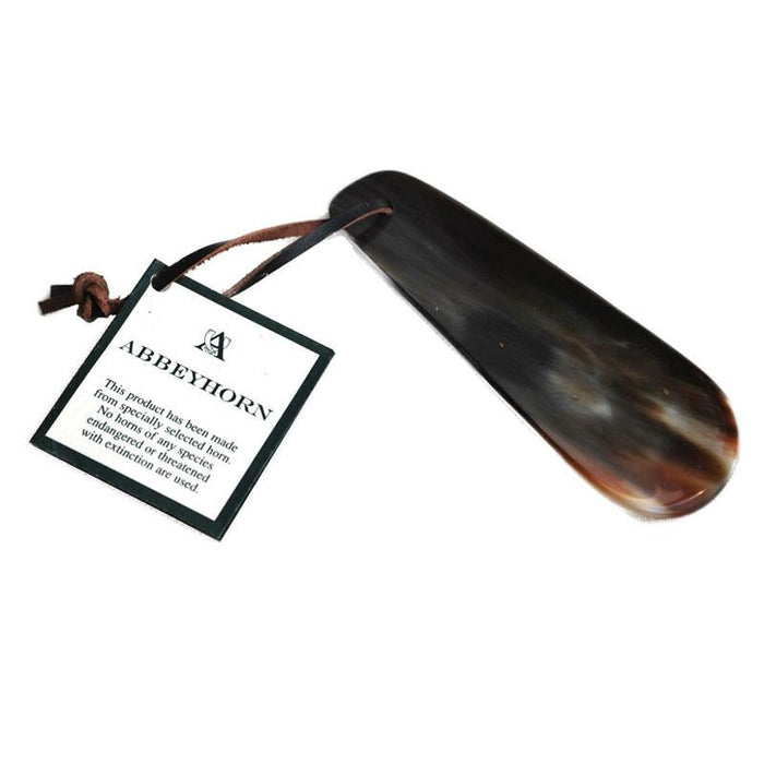 A flat-shaped shoe horn made of natural horn with a brown leather thong strap.