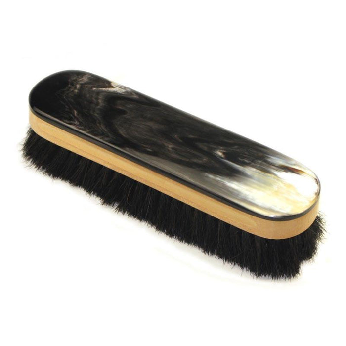 A handcrafted shoe polishing brush with a black and white oxhorn handle and dark bristles, presented on a plain background.