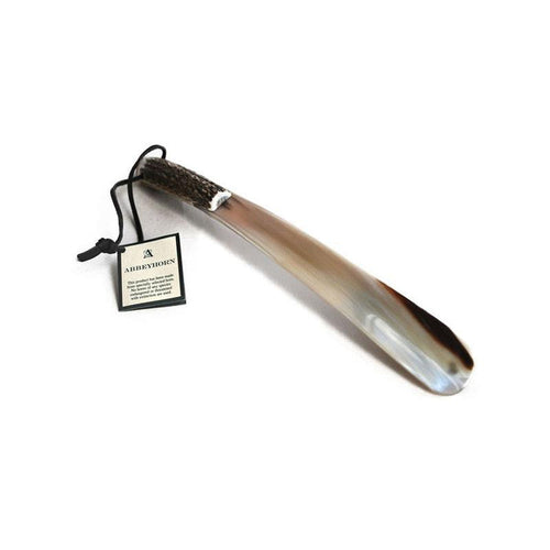 A real horn shoehorn with a stag antler handle and a leather thong strap, presented on a white background with a product tag indicating 'ABBEYHORN'.