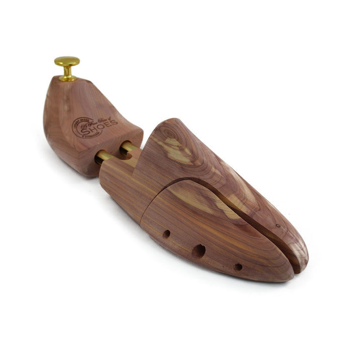 A pair of uncompressed cedar wood shoe trees with brass fitments, displayed in an open position.