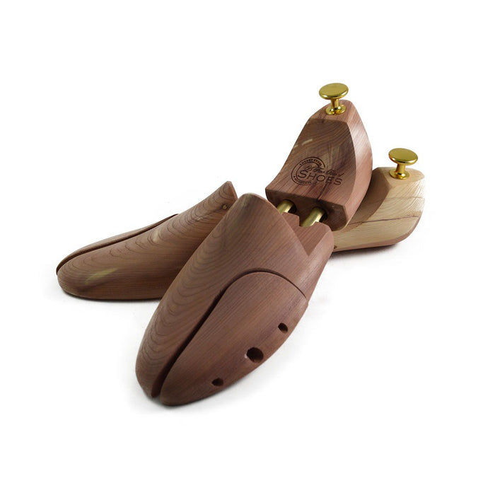 A pair of uncompressed cedar wood shoe trees with brass fitments, displayed in an open position.