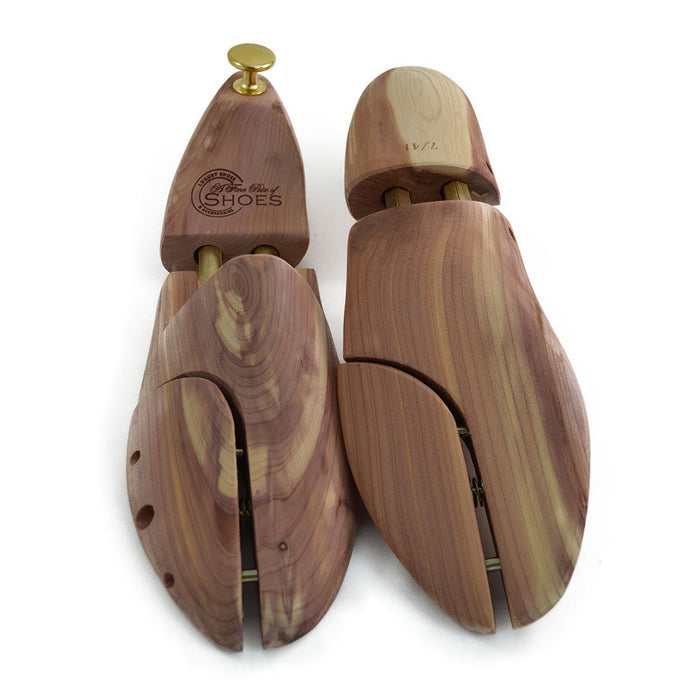 A pair of uncompressed cedar wood shoe trees with brass fitments, displayed in an open position.