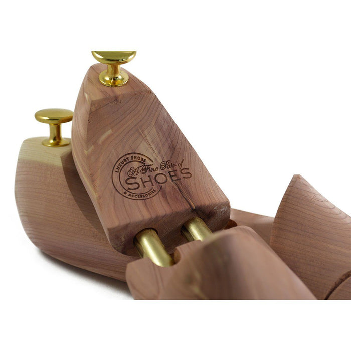 A pair of uncompressed cedar wood shoe trees with brass fitments, displayed in an open position.
