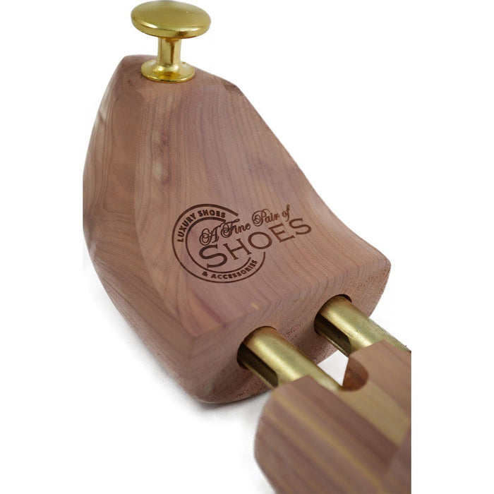 A pair of uncompressed cedar wood shoe trees with brass fitments, displayed in an open position.