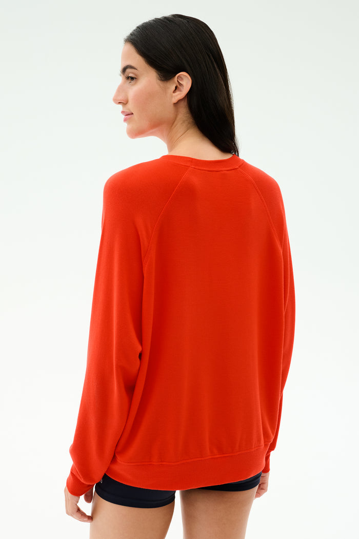 A person with long dark hair, seen from behind against a plain light background, wears the SPLITS59 Andie Oversized Fleece Sweatshirt in Lotus Red.