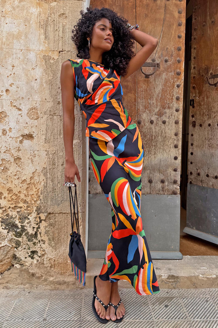 Banana A-Symmetric Top and matching skirt co-ord with vibrant banana motifs on a model against a stone wall.