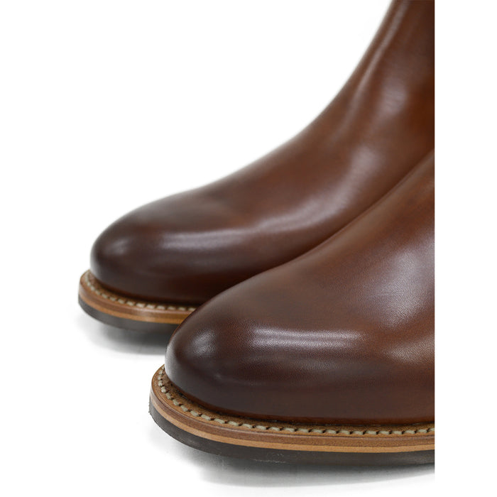 A brown Berwick 1707 Chelsea Boot with a pull tab on the side, showcasing a traditional round-toe shape and a natural welt with a Dainite rubber sole.