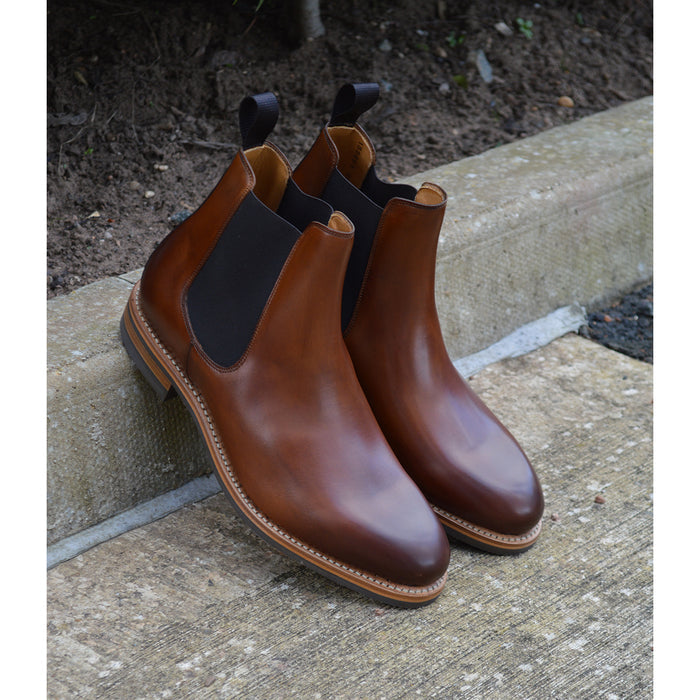 A brown Berwick 1707 Chelsea Boot with a pull tab on the side, showcasing a traditional round-toe shape and a natural welt with a Dainite rubber sole.