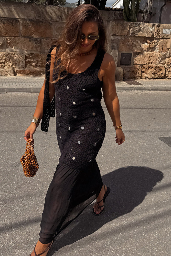 Black Crochet Alicia Dress with silver sequins and a gathered chiffon skirt, styled with a beaded bag on a sunny street.