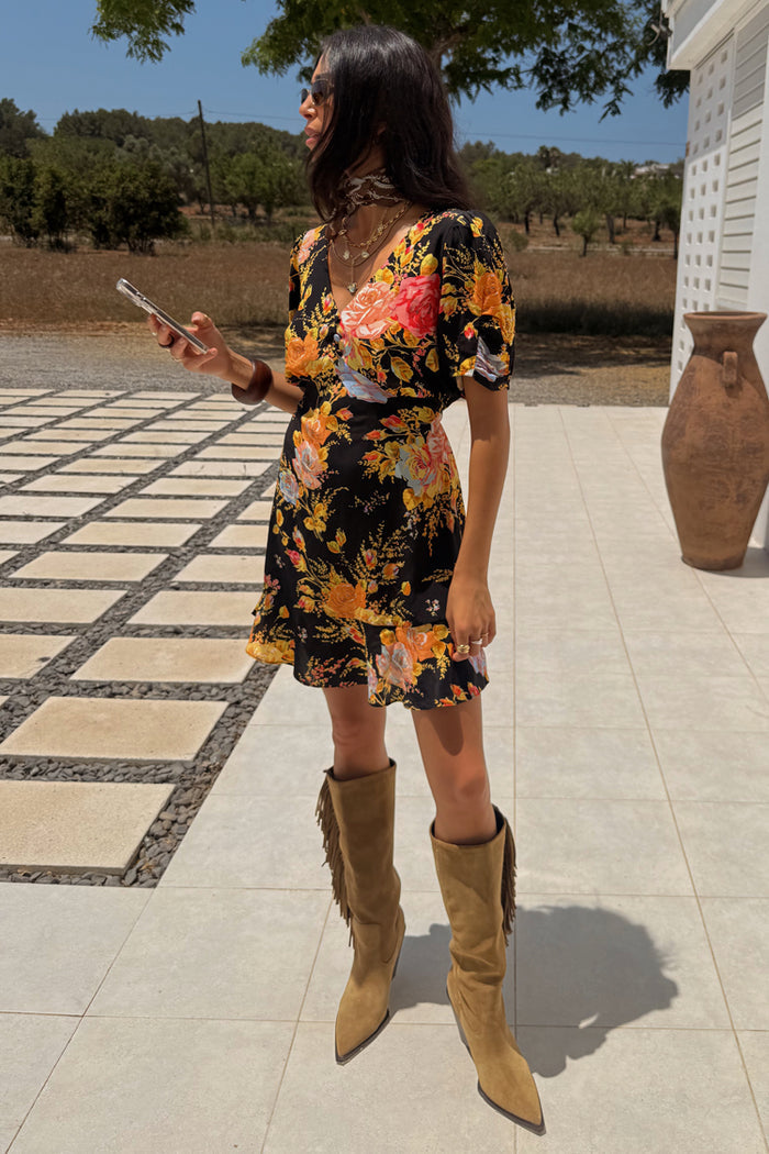 Black Sofia Mini Tea Dress with an orange and pink floral print and frill hem, styled with tan fringe boots.