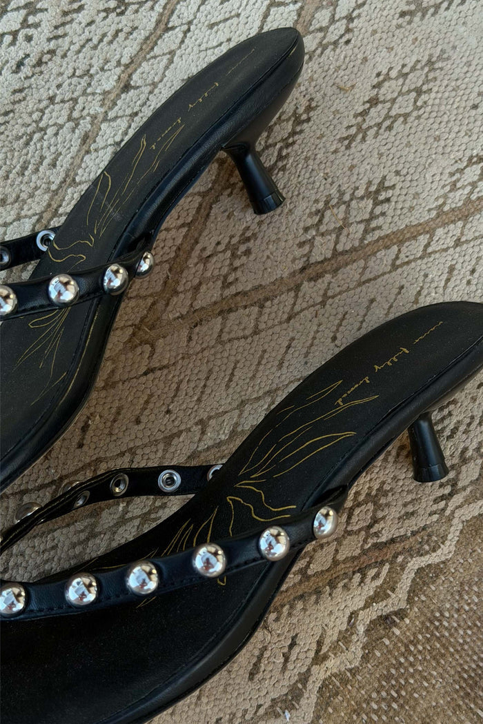 Black leather mules with silver studs, low kitten heels and a signature gold sun motif on the inner sole.