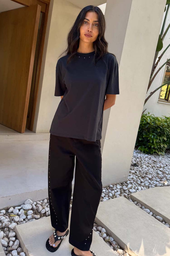 Black Studded T-Shirt in cotton with silver neckline studs and a relaxed fit, styled with black wide-leg trousers.
