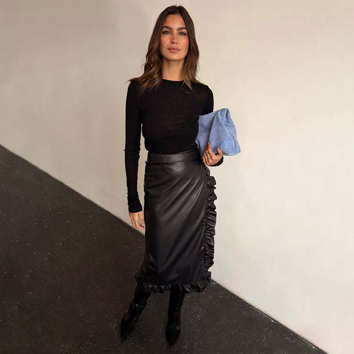 Black Vegan Leather Ruffle Jaspre Skirt with side ruffle detailing, styled with a long-sleeve top and blue clutch.