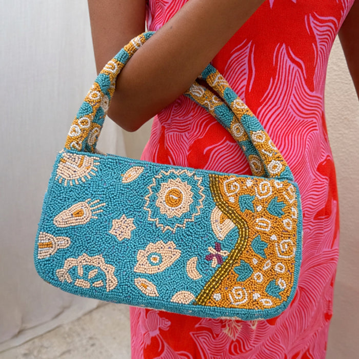 Blue and Yellow Morocco Beaded bag with hand-embellished glass beads and iconic NFD motifs, held by a model.