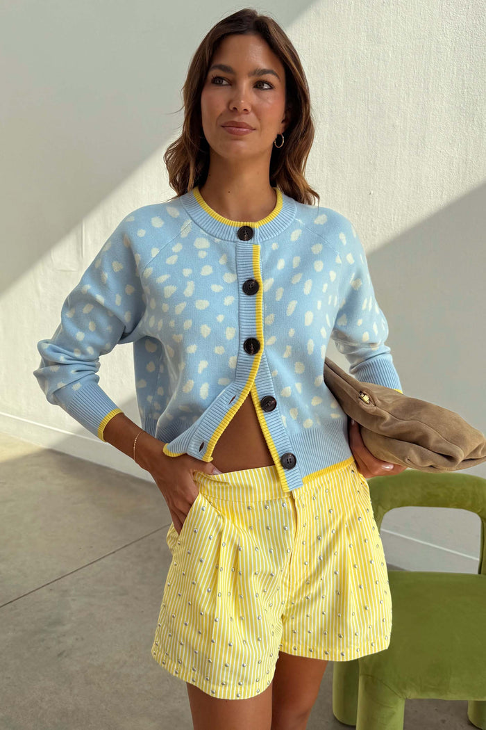 Blue Fawn Cheryl Cardigan in a soft knit with a spotted deer print and yellow trim, styled with striped shorts.