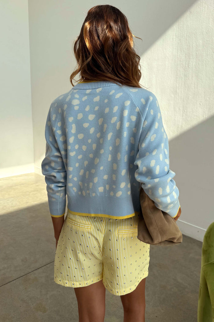 Blue Fawn Cheryl Cardigan in a pale blue deer print knit, styled with yellow striped shorts from the back.
