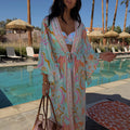 Blue Dreamer Maxi Kimono with palm and sun motifs, featuring a flowy silhouette and tie waist for a poolside look.