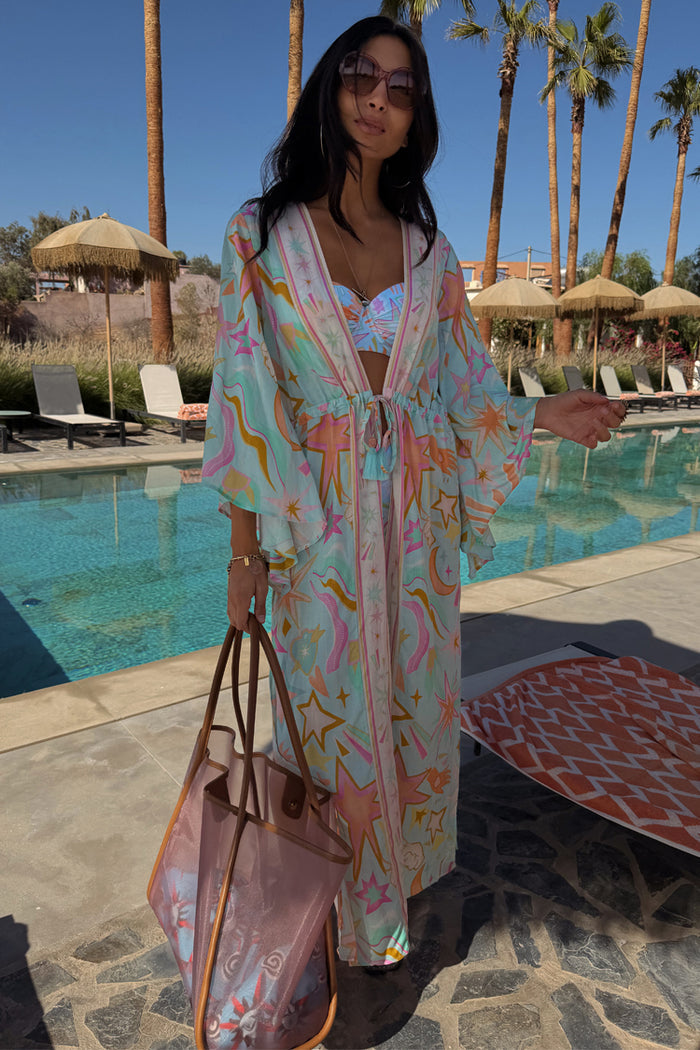 Blue Dreamer Maxi Kimono with a light blue celestial print, wide sleeves and tie waist in a poolside setting.