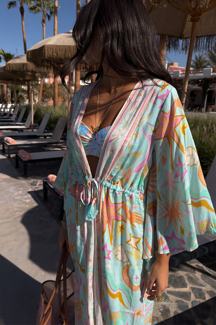 Blue Dreamer Maxi Kimono in light blue with sun and heart motifs, worn poolside with matching swimwear.