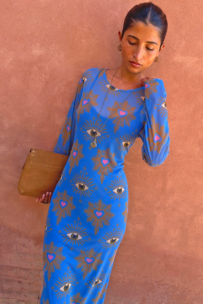 Blue Eye Mesh Maxi Dress featuring heart motifs, styled with a tan clutch bag and gold jewellery.