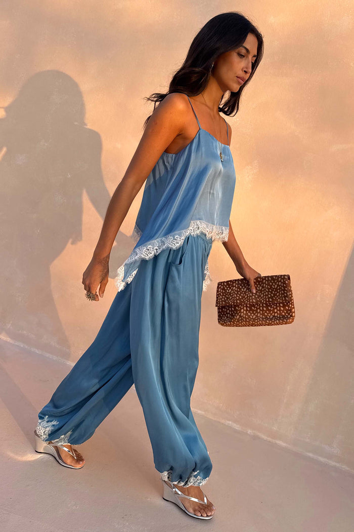 Blue Lace Balloon Trousers in a washed blue satin with delicate lace trims and elasticated ankles on a walking model.