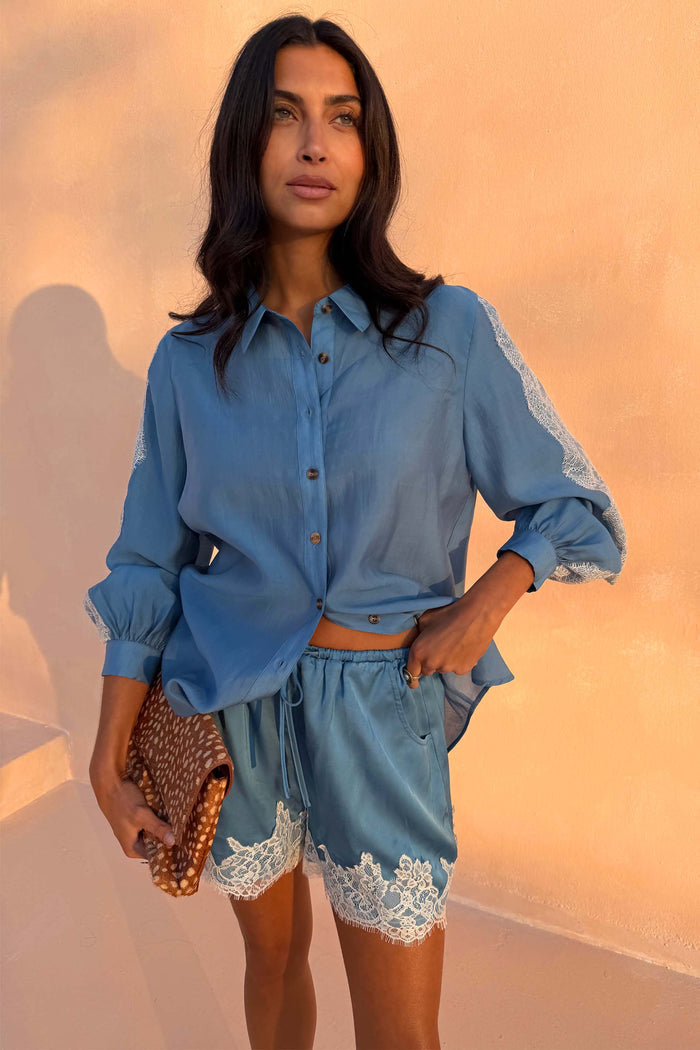 Blue Lace Marley Shirt with white lace sleeve inserts, styled with matching lace shorts and a patterned clutch.