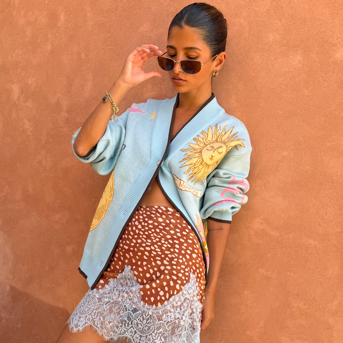 Blue Mystical Cardigan in light blue knit with sun and moon jacquard motifs and contrast brown trims.