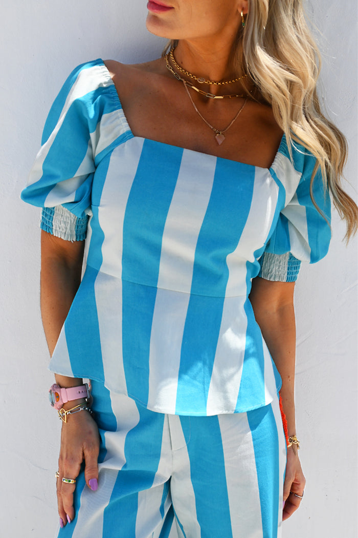 Blue Stripe Kiki Top featuring puffed sleeves and a peplum hem detail on a model.