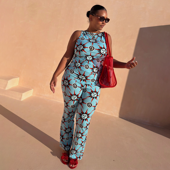 Blue Sun Foldover Trouser with sun and swirl motifs, styled as a co-ord with a matching vest in a sunny setting.
