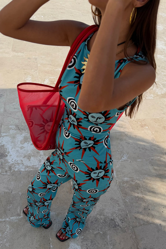 Blue Sun Foldover Trouser with hand-painted sun motifs, styled as a co-ord with a matching top and red bag.