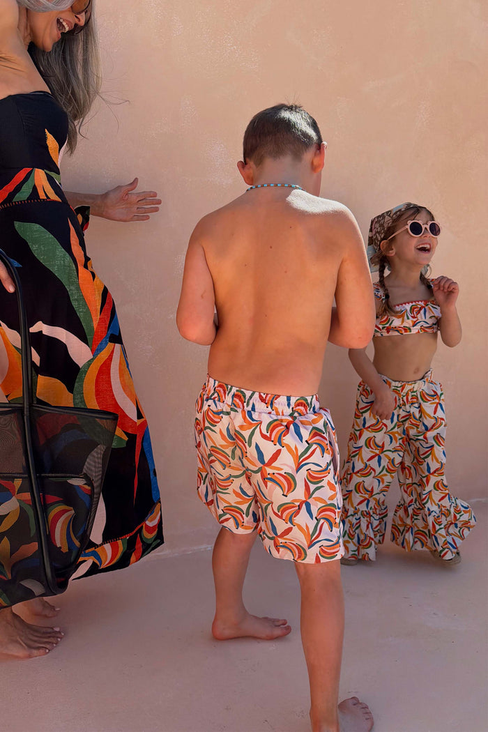 Boy's cream banana print swim shorts with a multi-coloured pattern, part of a matching family vacation set.