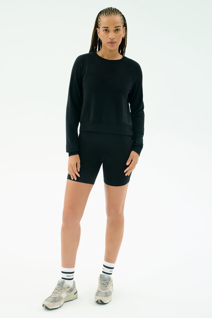 A person faces forward against a plain white background, wearing the SPLITS59 Brooks Fleece Long Sleeve Sweatshirt in black. This premium crewneck pullover is quality made in Los Angeles.