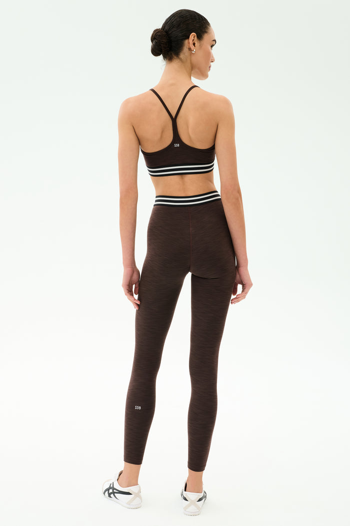 A person stands with their back to the camera, wearing the SPLITS59 Cali Active Rib Bra in Heather Dark Chocolate with matching high-waisted leggings, set against a plain white background.