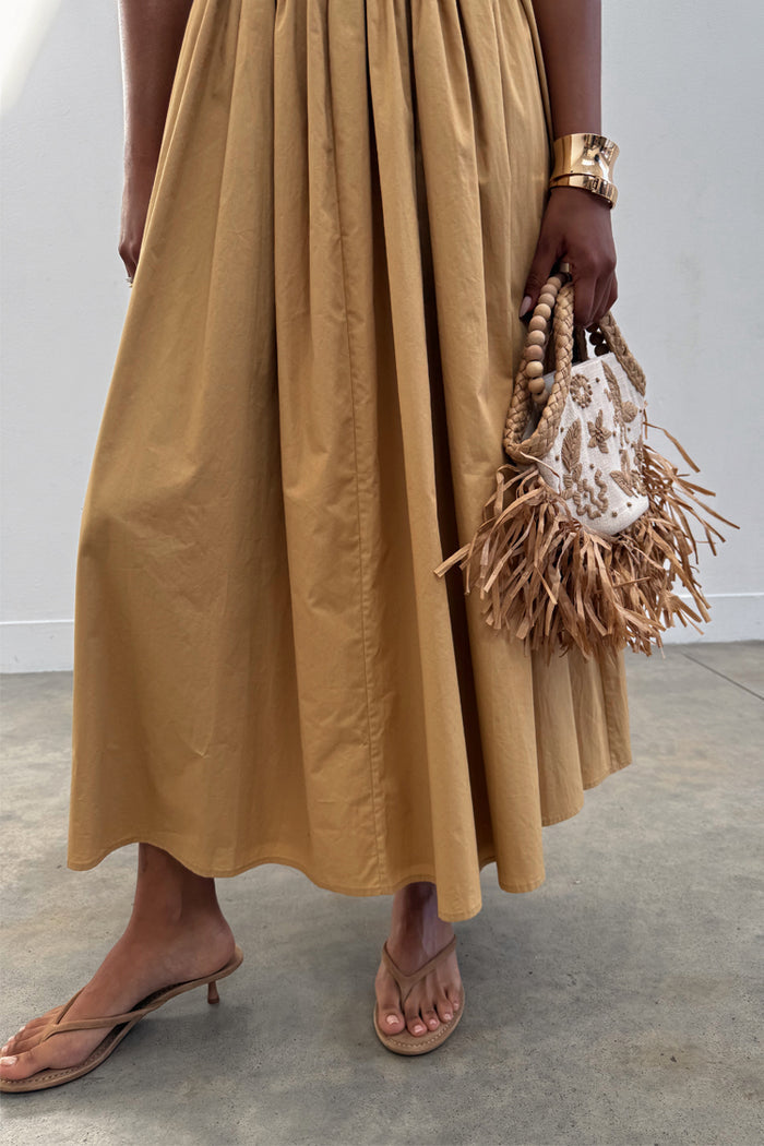 Camel Monika Dress with a pleated skirt, styled with a beaded fringe bag and tan kitten heel sandals.