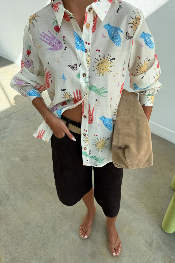 Cream Celestial Marley Shirt with an oversized fit and sun motifs, styled with dark brown shorts and a tan bag.