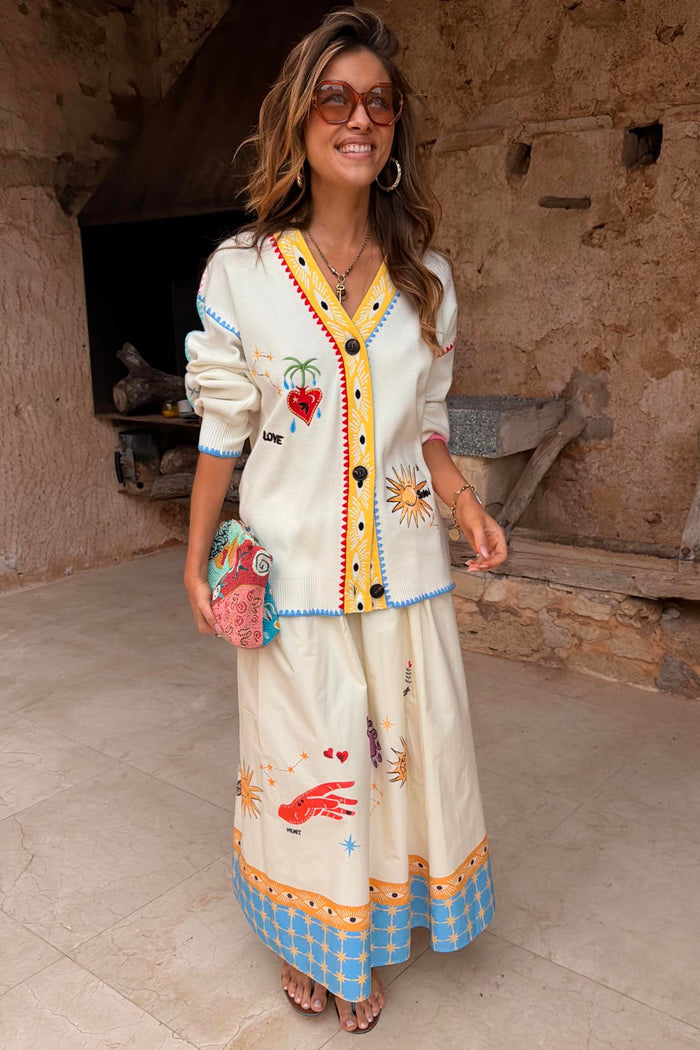 Celestial Talia Skirt in white cotton with colourful sun and palm motifs, worn with a matching cardigan.