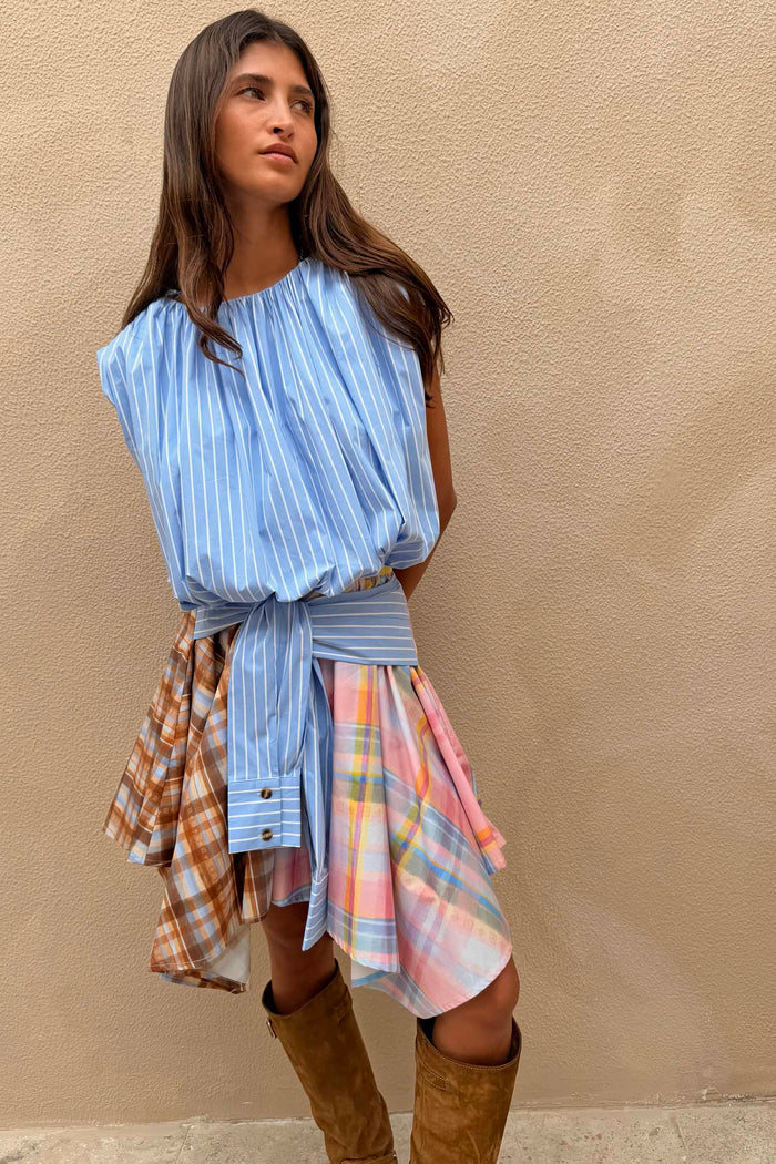 Check Asymmetric Mini Skirt featuring mixed check patterns and a blue stripe tie-waist detail, paired with brown boots.