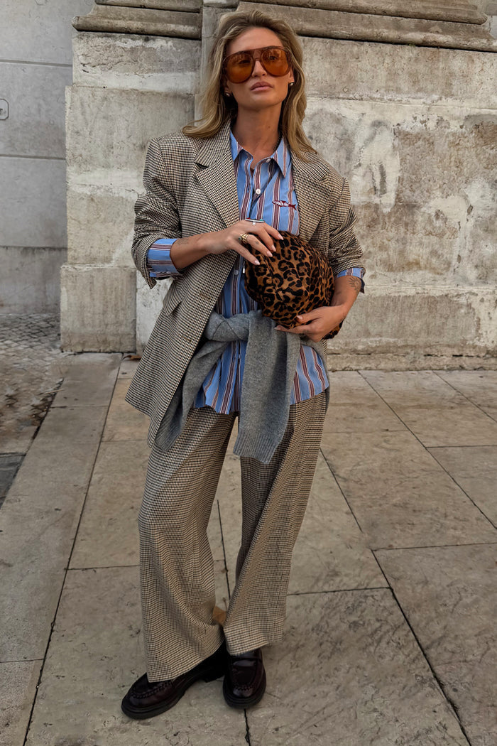 Grey check trousers and matching blazer co-ord styled with a blue striped shirt and leopard print clutch bag.