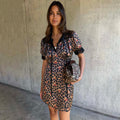 Cherry Leopard Mini Lyla Dress with black lace trims, tie neck and puff sleeves, styled with a coordinating clutch bag.