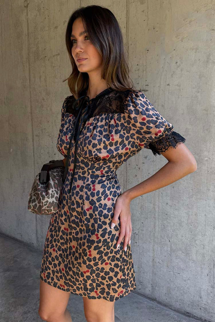 Iconic Cherry Leopard Mini Lyla Dress with black lace trims and tie neck, styled with a matching leopard print bag.