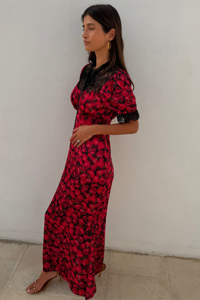 Red Cherry Lyla Dress with a cherry print, black lace detailing on the neck and cuffs, and a tie neckline.