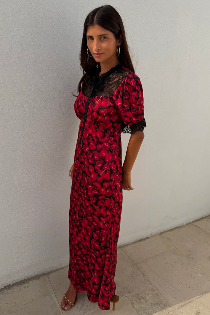 Red Cherry Lyla Dress with an all-over cherry print, black lace at the neckline and cuffs, and a neck tie.