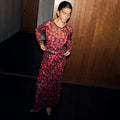 Cherry Mesh Dorris Skirt co-ord in a red cherry print, styled with leopard print heels against a wooden wall.