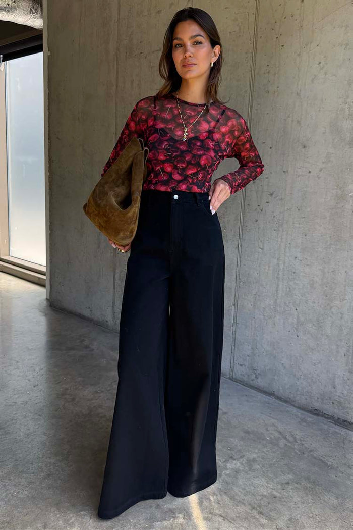 Cherry Mesh Long Sleeve Top featuring a red cherry print, paired with black wide-leg trousers and a suede bag.