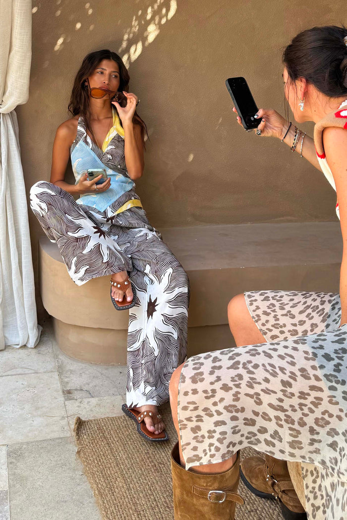 Chocolate Soleil Ellie Trousers and wrap top in a sun motif, styled as a wide-leg co-ord in a Mediterranean setting.