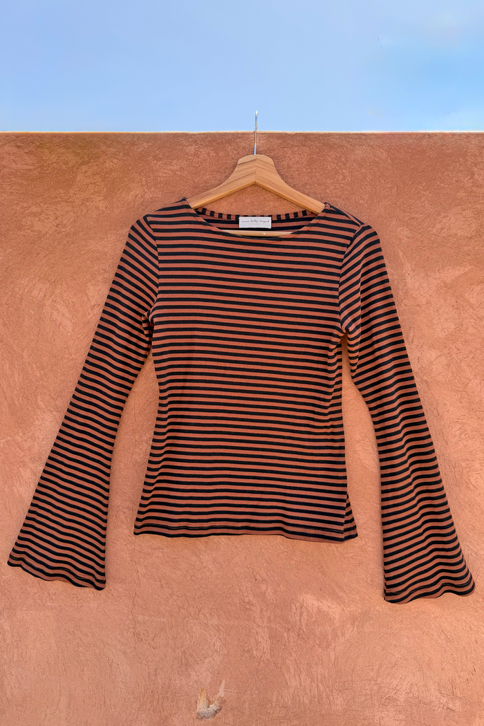 Ribbed Chocolate Stripe Top with flared bell sleeves hanging on a wooden hanger against a terracotta wall.