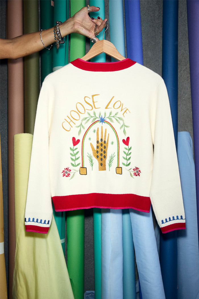 White Choose Love Cardigan with red ribbed trims and vibrant back embroidery of a hand, florals, and text.