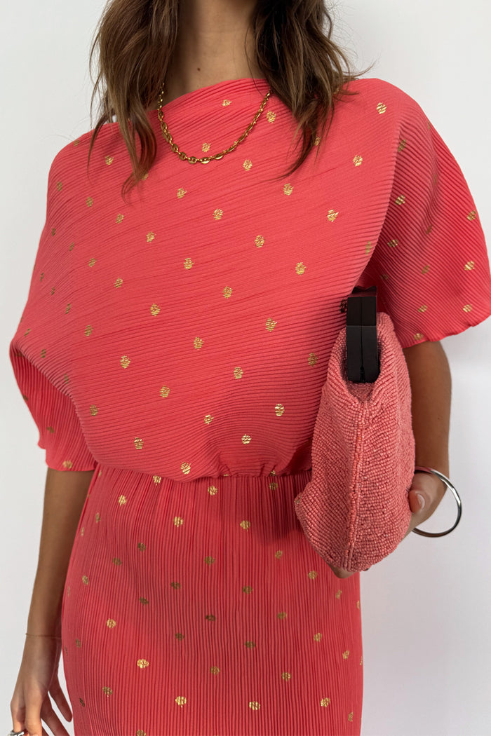 Coral Plisse Tilly Dress with gold flecks and an off-the-shoulder neckline, styled with a pink beaded clutch.