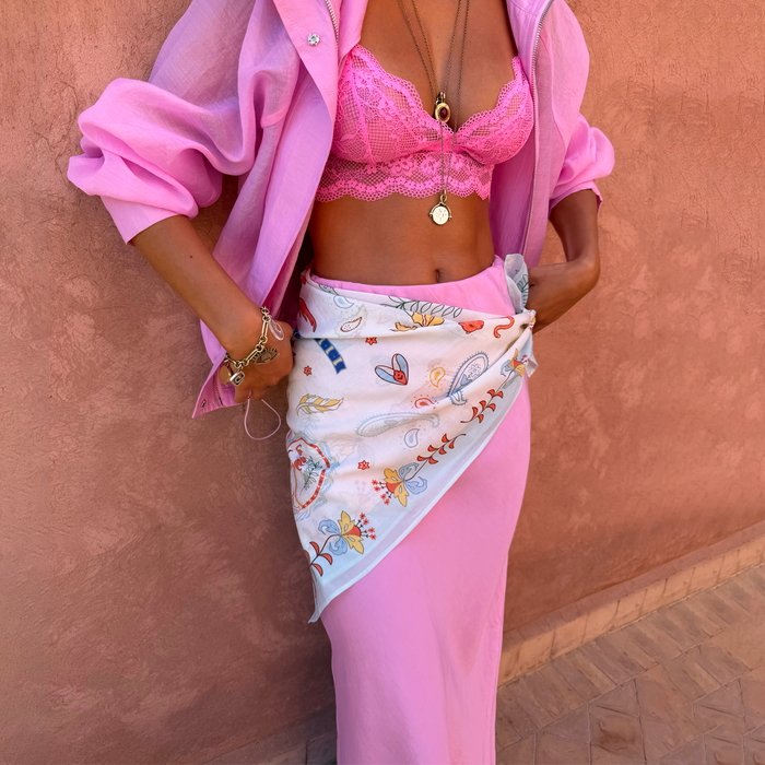 Cream Bandana in Tigress Print styled as a multi-wear waist wrap over a pink skirt, featuring paisley patterns.