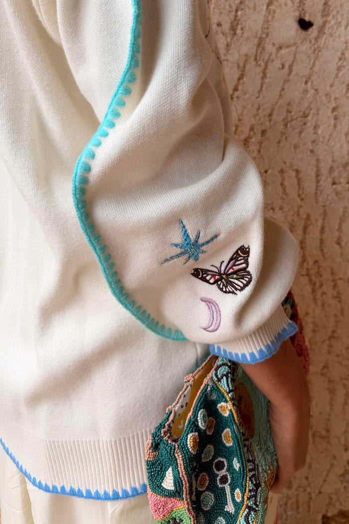 Cream Celestial Martha Cardigan sleeve featuring embroidered cosmic motifs and blue blanket stitch trim.